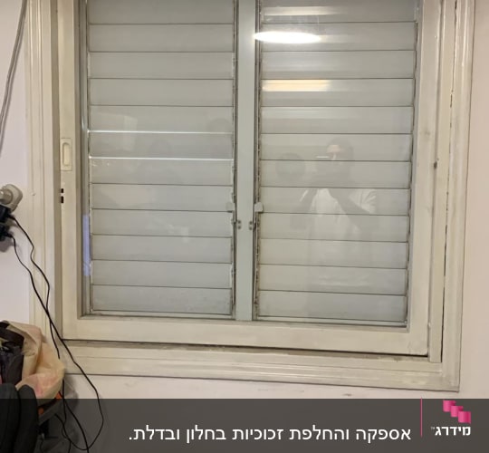 חלון עם תריסים סגורים ומכשיר מיזוג אוויר